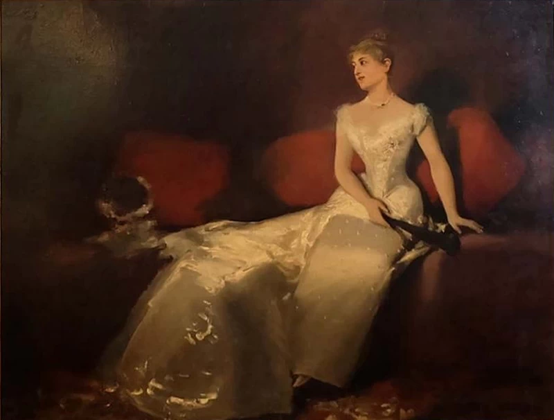 Giovane donna in abito da sera di seta con ventaglio sul divano
